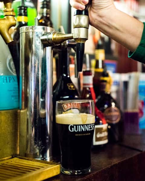 someone pouring guinness from tap into glass