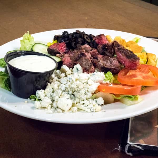 salad with romaine, tomatoes, croutons, cucumbers, grilled steak slices, black olives, blue cheese crumbles and a side of blue cheese dressing