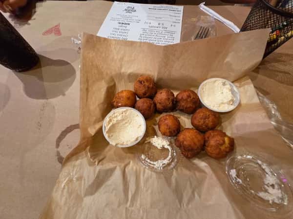 Golden-brown hush puppies served with creamy dipping sauce on parchment paper — a classic Southern-style appetizer.
