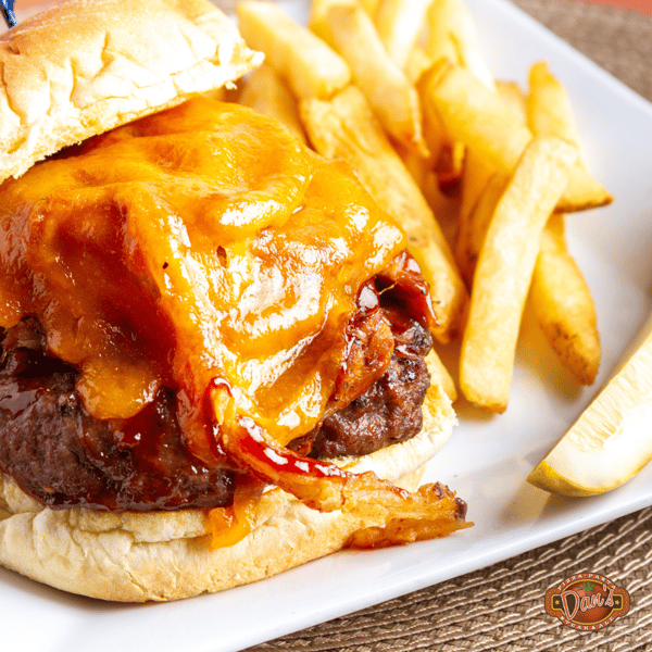 cheeseburger topped with melted cheddar served with crispy fries on a plate