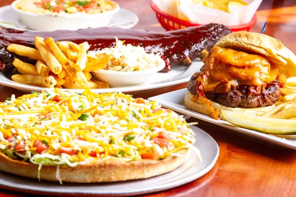 classic American comfort food spread with burgers, fries, and loaded pizza on a restaurant table