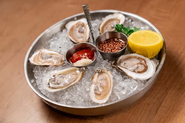 plate of oysters on ice with sauce