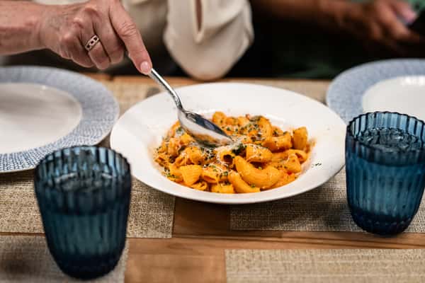Hand dipping a spoon into pasta
