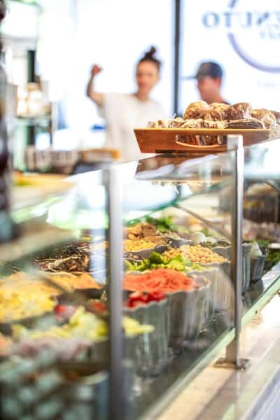 Salad bar behind a glass window with pastries on top