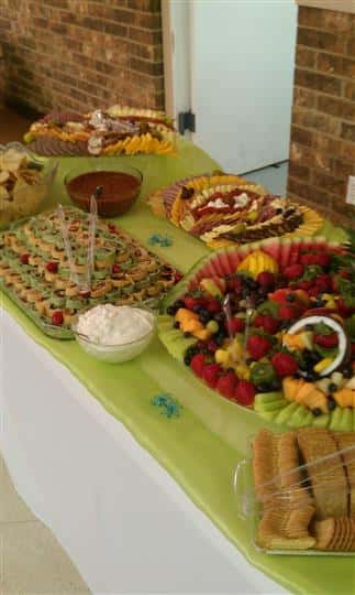 A decorated buffet with bites fruit, cold cuts and dipping sauces