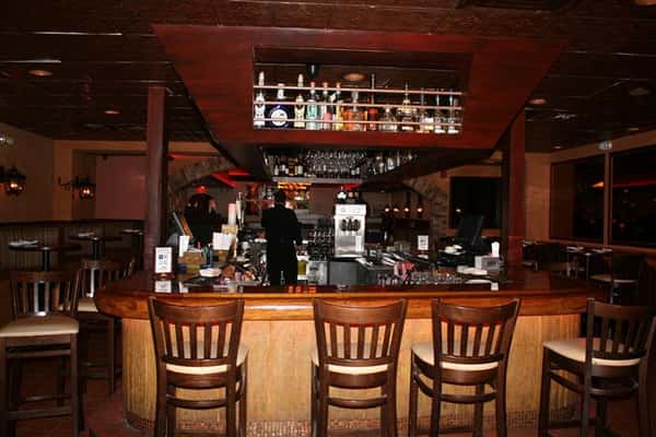 photo of the bar with bottles of liquor lined up above the bar and bar stools around it