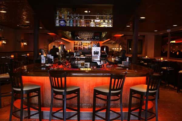 photo of the bar with bottles of liquor lined up above the bar and bar stools around it