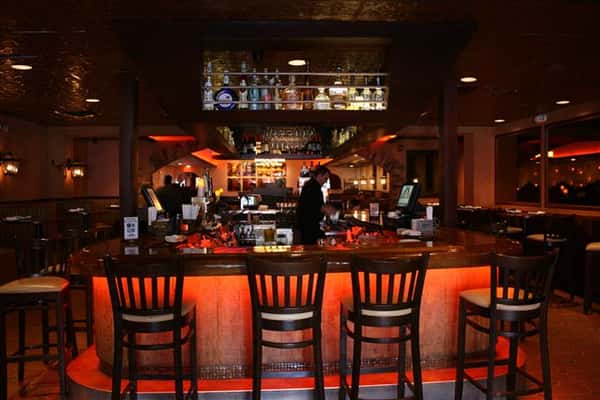 photo of the bar with bottles of liquor lined up above the bar and bar stools around it