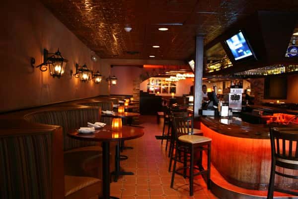 a view of the bar with barstools and side tables with bar stools