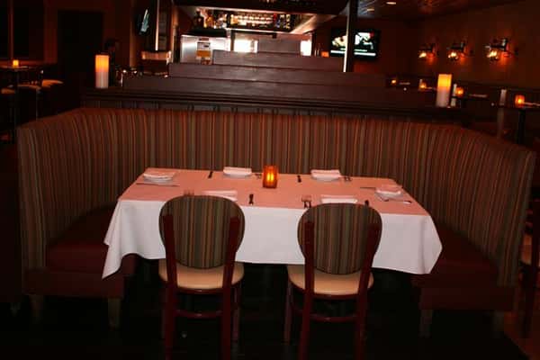 white tablecloth table with a candle in the middle, in a booth with chairs around