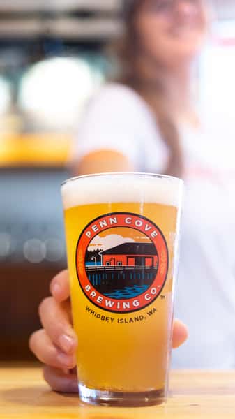 Waitress holding out a Penn Cove Brewing glass