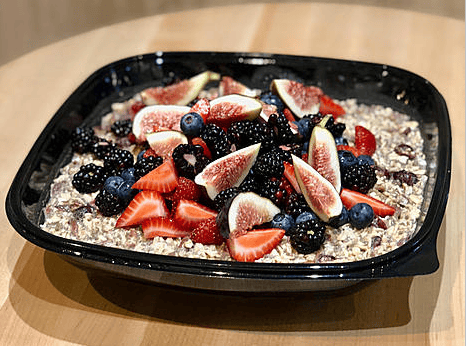 A bowl of oatmeal topped with fresh figs, strawberries, blackberries, and blueberries.