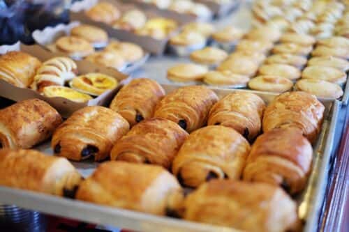 A selection of freshly baked pastries, including chocolate croissants and other assorted items, arranged on a tray.