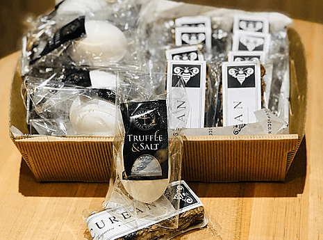 A box of packaged treats, including Truffle & Salt bars and other items, each labeled with black and white branding.