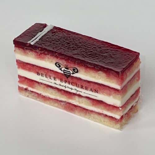 A layered cake with raspberry filling, alternating with cream layers and topped with a glossy red jelly, featuring a branded logo.