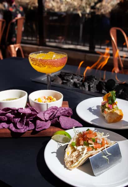 Street tacos, house-made dips, and a handcrafted margarita served beside a fire feature on a stylish outdoor patio.