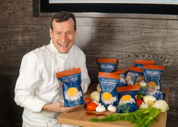 Chef Jean-Francis poses with several bags of his fish soup