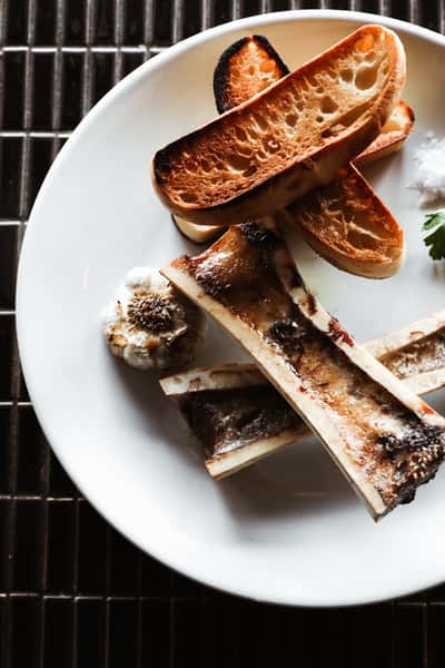 Savor the richness of bone marrow entree at Kayne Prime, served with toasted bread, presenting a delectable culinary masterpiece.