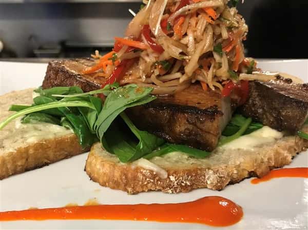Pork loin with slaw over greens and bread
