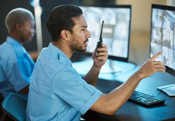 Security Guard with a radio looking to a computer Screen