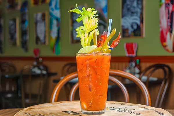 A classic Bloody Mary garnished with a tall stalk of celery and pickled vegetables in a highball glass.