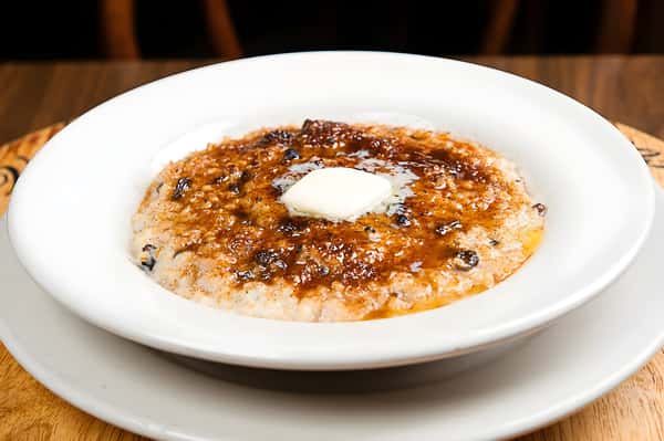 A bowl of oatmeal or grits, topped with a pat of melting butter and a drizzle of brown sugar or syrup.