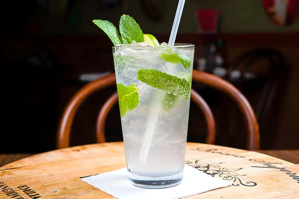 A refreshing mojito or mint-based cocktail with fresh mint leaves and a straw, featuring a clear, carbonated appearance.