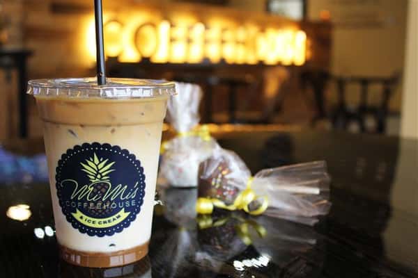 an iced coffee with a bag of chocolate truffles on a table