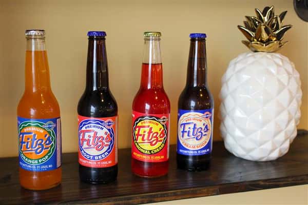 four different fitz's soda bottles on a counter next to a ceramic pineapple