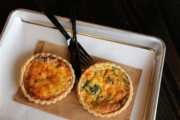 two mini quiches sitting on a napkin with a fork and knife