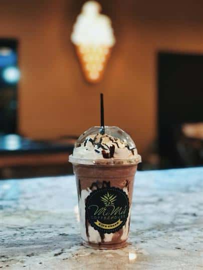 an iced frappecino with whipped cream and chocolate drizzle on a granite countertop