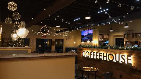 a view of the indoor coffeehouse with christmas lights lining the walls and an illuminated "coffeehouse" sign