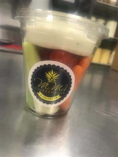a cup of celery, tomatoes, and carrots with ranch dipping sauce