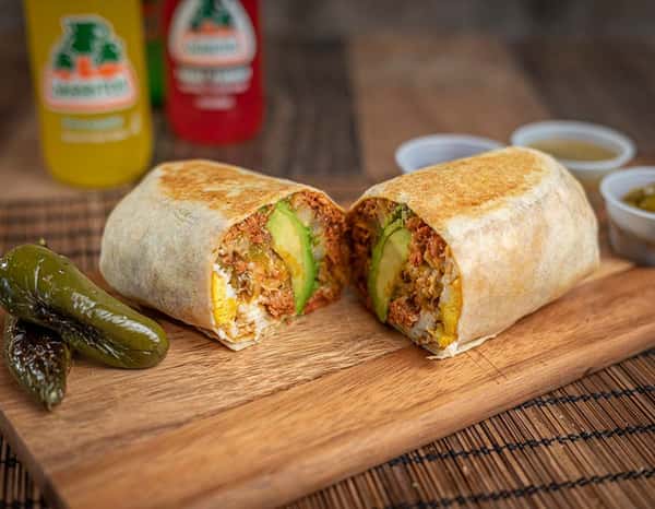 Grilled burrito sliced in half, revealing a savory mix of seasoned meat, avocado slices, scrambled eggs, and melted cheese wrapped in a toasted flour tortilla — a satisfying Mexican-style meal perfect for breakfast or lunch.