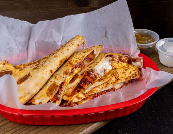 Basket of golden-brown folded quesadillas filled with melted cheese and seasoned meat, served in a red plastic tray lined with parchment paper — a delicious Mexican comfort food ideal for casual dining and takeout.