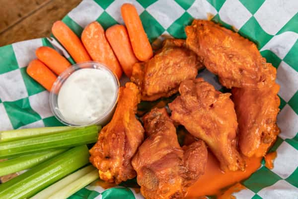 Buffalo chicken wings coated in hot sauce, served with celery sticks, baby carrots, and a side of ranch dressing.