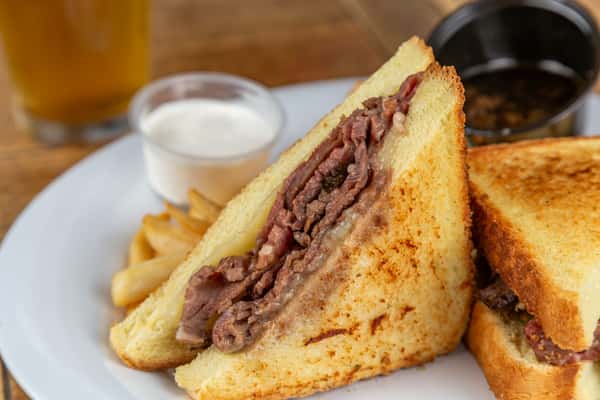 Melted cheese and sliced roast beef on toasted bread, served with fries, au jus, and creamy horseradish sauce.