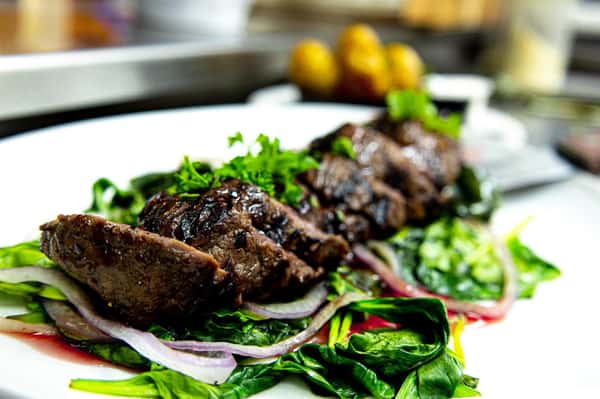 seasoned steak sliced over a bed of greens