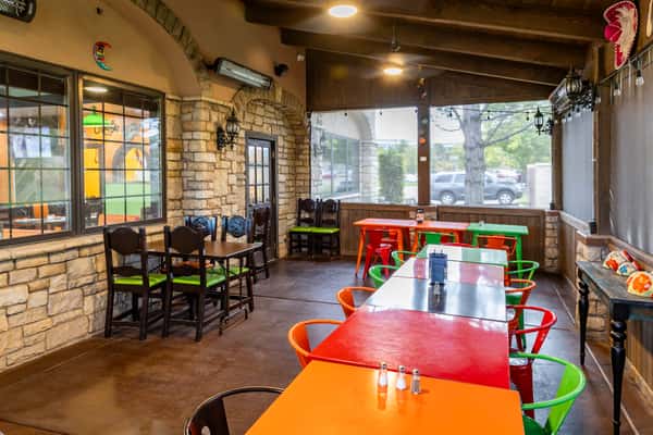 Bright dining area with orange tables, colorful chairs, and large windows