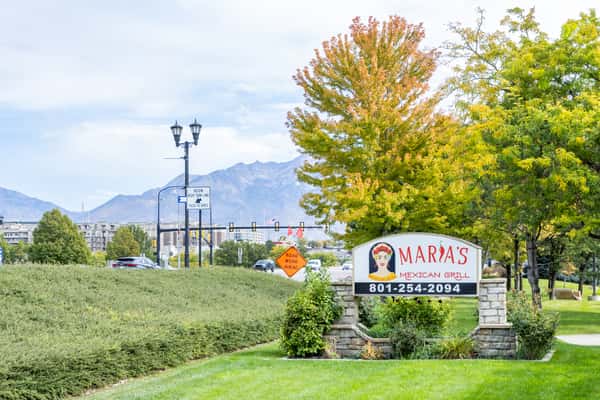 Maria's Mexican Grill roadside sign surrounded by lawn, trees, and landscaping