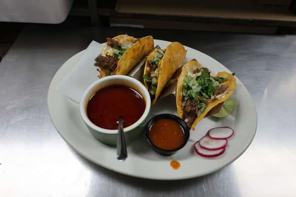 Street tacos with cilantro and onion, served with red salsas and radishes