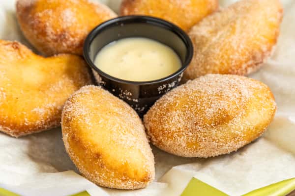 Golden sugar-dusted Mexican pastry bites served with creamy dipping sauce