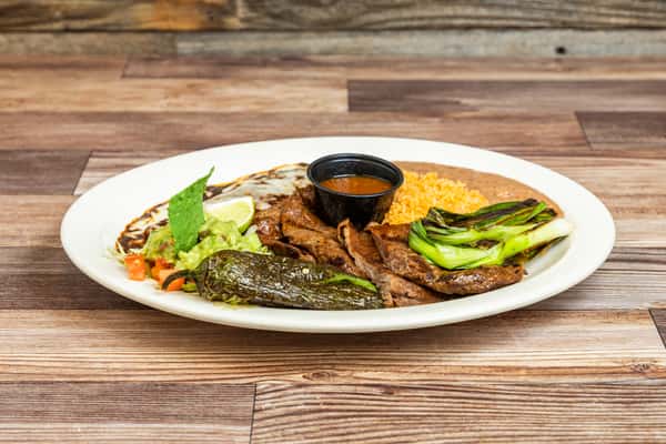 Grilled Tampiqueña steak served with beans, rice, guacamole, and fresh vegetables
