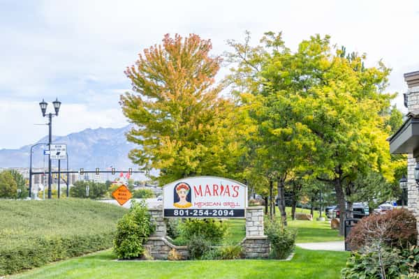 Maria's Mexican Grill roadside sign framed by trees and landscaped greenery