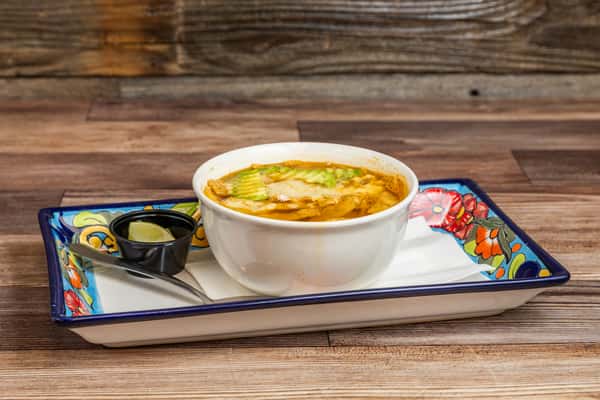 Warm Mexican tortilla soup served with fresh avocado and traditional accompaniments