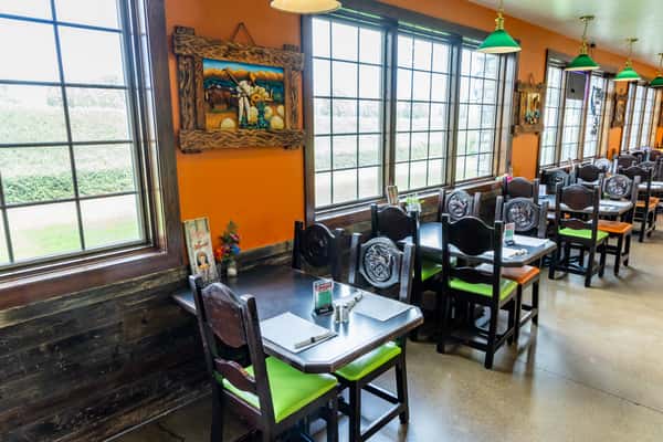 Dining area with dark wood tables, colorful chairs, and large windows