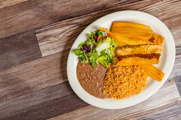 Traditional Mexican tamales served with rice, beans, lettuce, and fresh garnish
