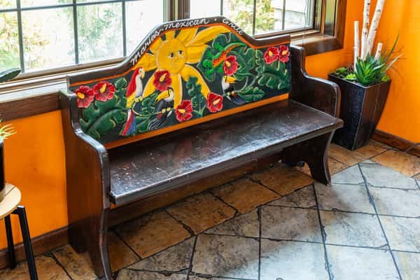 Colorfully painted bench with Mexican-inspired artwork inside Maria's Mexican Grill