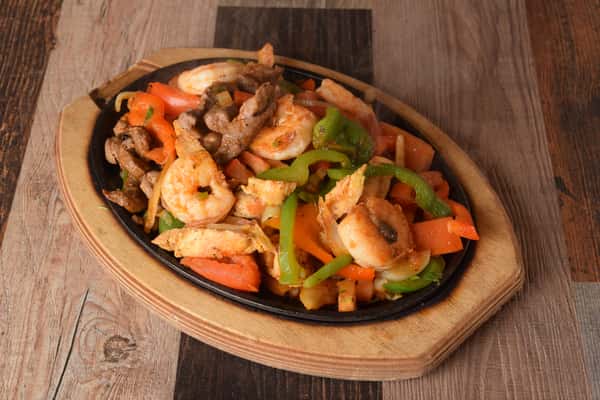Sizzling fajitas with shrimp, steak, chicken, bell peppers and onions
