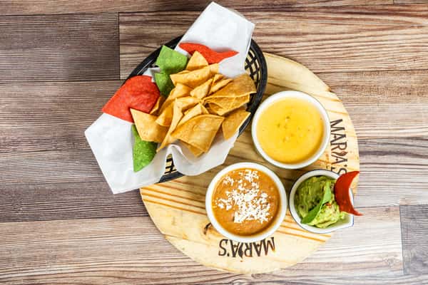 Three house dips served with crispy tortilla chips and colorful fresh garnish